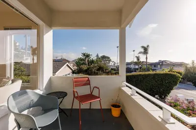 a balcony with a red chair and two chairs at ENC-1035 - Charming Coastal Cottage in Encinitas