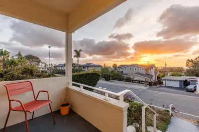 a red chair on a balcony with a view of a street at ENC-1035 - Charming Coastal Cottage in Encinitas
