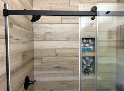 a shower in a bathroom with a wooden wall at Hilltop Penthouse Cottage with Sweeping Views in Fallbrook