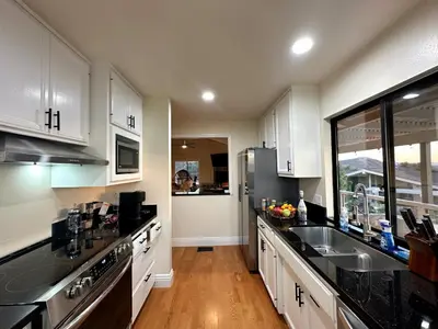 a kitchen with white cabinets and a stainless steel refrigerator at Hilltop Penthouse Cottage with Sweeping Views in Fallbrook