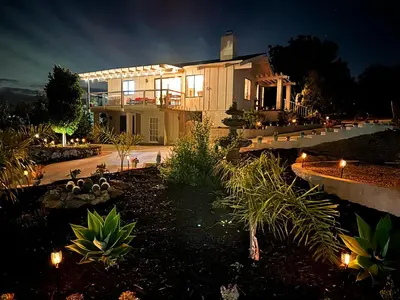a large house with lights in a yard at night at Hilltop Penthouse Cottage with Sweeping Views in Fallbrook