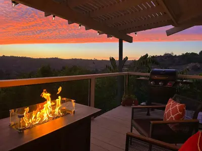 a fire pit on a deck with a sunset in the background at Hilltop Penthouse Cottage with Sweeping Views in Fallbrook