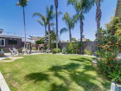 a yard with a lawn with palm trees and a house at Bay Park Gem - Fully Loaded in San Diego