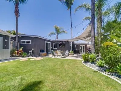 a yard with chairs and a house with palm trees at Bay Park Gem - Fully Loaded in San Diego
