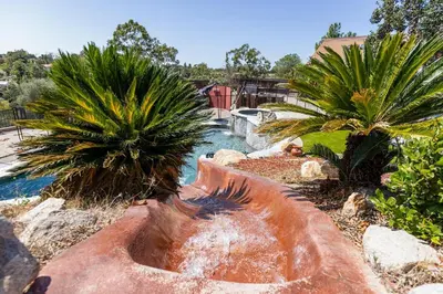 a backyard with a pool with a waterfall and palm trees at San Diego Getaway, Views Pool Hot Tub & Game Room in Valley Center