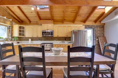 a kitchen with a wooden table with chairs and a refrigerator at 4 Mi to Lake Wohlford Cabin in Escondido in Valley Center