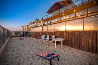 a building on the beach with a table and chairs at Oceanfront Getaway - Ocean Views - Fire Pit - BBQ - Beach Access in Carlsbad