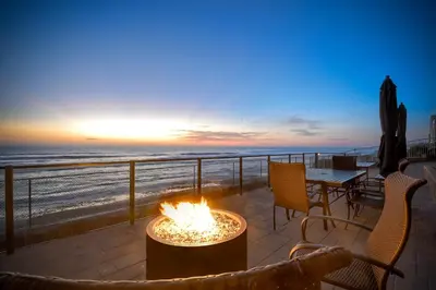 a fire pit on a patio overlooking the beach at sunset at Oceanfront Getaway - Ocean Views - Fire Pit - BBQ - Beach Access in Carlsbad