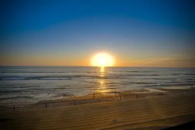 a sunset on the beach with the sun setting at Oceanfront Getaway - Ocean Views - Fire Pit - BBQ - Beach Access in Carlsbad
