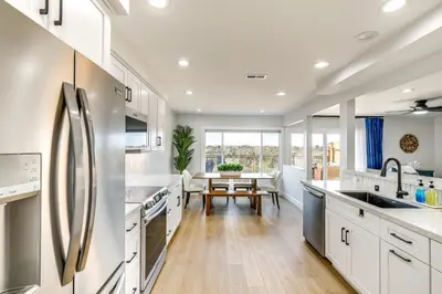 a kitchen with white cabinets and a dining table at Balconies and Views Modern Abode in Poway! in Poway
