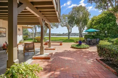a patio with a table and chairs and an umbrella at Gated Lakefront Estate - Seaside with Private Beach in Oceanside