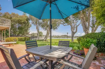 a wooden table with chairs and an umbrella at Gated Lakefront Estate - Seaside with Private Beach in Oceanside