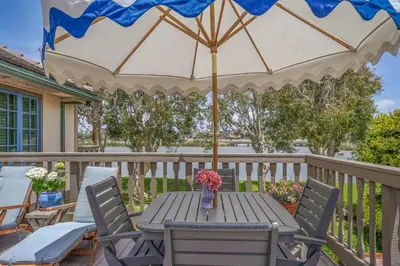 a wooden table with an umbrella on a deck at Gated Lakefront Estate - Seaside with Private Beach in Oceanside