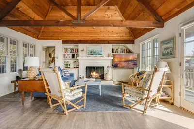 a living room with a fireplace and wooden ceilings at Gated Lakefront Estate - Seaside with Private Beach in Oceanside