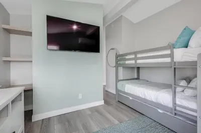 a small bedroom with bunk beds and a flat screen tv at Luxury Meets Coastal Charm in North Mission Beach in San Diego