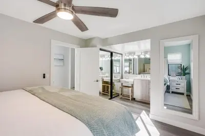 a white bedroom with a ceiling fan and a bathroom at Luxury Meets Coastal Charm in North Mission Beach in San Diego
