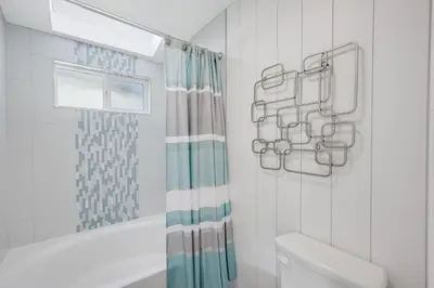 a bathroom with a toilet and a shower curtain at Luxury Meets Coastal Charm in North Mission Beach in San Diego