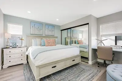 a bedroom with a bed and a desk and a mirror at Luxury Meets Coastal Charm in North Mission Beach in San Diego