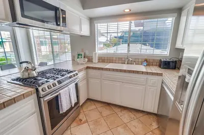 a white kitchen with a stove and a sink at Half block to bay steps to ocean AC large patio in San Diego