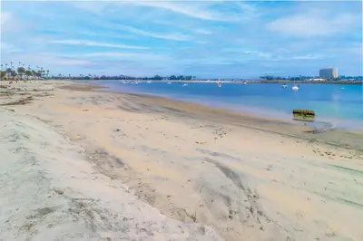 a bench on a beach with boats in the water at Half block to bay steps to ocean AC large patio in San Diego
