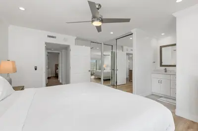 a white bedroom with a large bed and a mirror at Trackside Tranquility - TC522B in Solana Beach