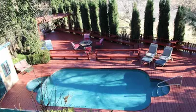 a swimming pool with benches and chairs and trees at Eaglenest Inn with Pool & Seasonal SPA in Julian