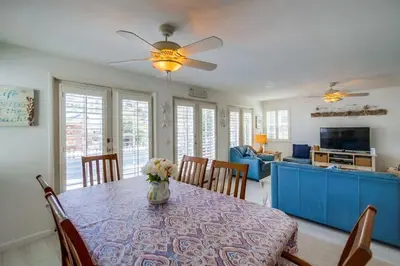 a dining room table with a vase of flowers on it at Luxury summer house feet from bay & ocean patios in San Diego