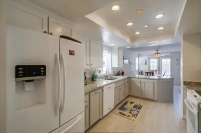 a kitchen with white cabinets and a white refrigerator at Luxury summer house feet from bay & ocean patios in San Diego