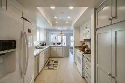 a large kitchen with white cabinets and white appliances at Luxury summer house feet from bay & ocean patios in San Diego