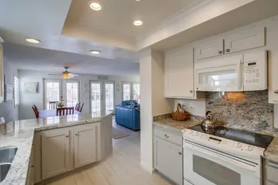 a kitchen with white cabinets and a living room at Luxury summer house feet from bay & ocean patios in San Diego