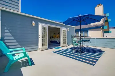 a patio with a blue bench and an umbrella at Luxury summer house feet from bay & ocean patios in San Diego