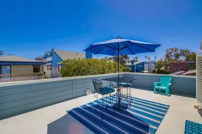 a table and chairs and an umbrella on a patio at Luxury summer house feet from bay & ocean patios in San Diego