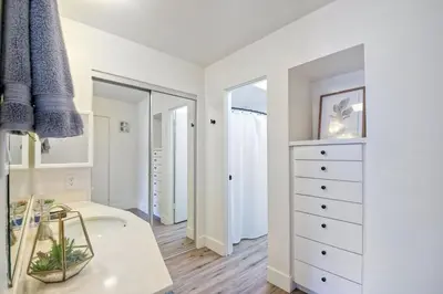 a white bedroom with a dresser and a mirror at 2003 Costa Del Mar Road - Unit 676 in Carlsbad