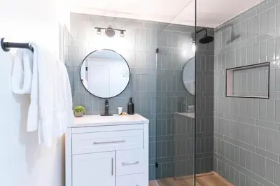 a bathroom with a shower with a sink and a mirror at Beachwalk Villas in Carlsbad