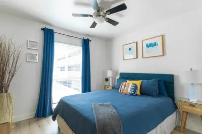 a bedroom with a blue bed and a ceiling fan at Beachwalk Villas in Carlsbad