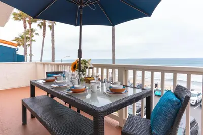 a table with chairs and an umbrella on a balcony at Beachwalk Villas in Carlsbad