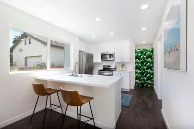 a kitchen with white cabinets and a counter and stools at Comstock in San Diego