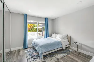 a bedroom with a bed with blue curtains and a window at MV Retreat Pool Spa Fire Pit Family Friendly in Mission Viejo