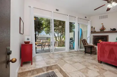 a living room with a fireplace and sliding glass doors at Bask in the Breeze - DMBC146N in Solana Beach