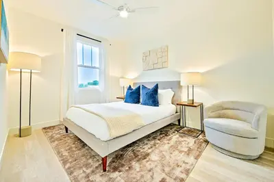 a white bedroom with a bed and a chair at 343 Oak Avenue in Carlsbad