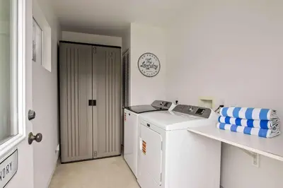 a white laundry room with a washing machine and a clock at Coastal Retreat 1BR Steps to Ocean & Peek Views in San Diego