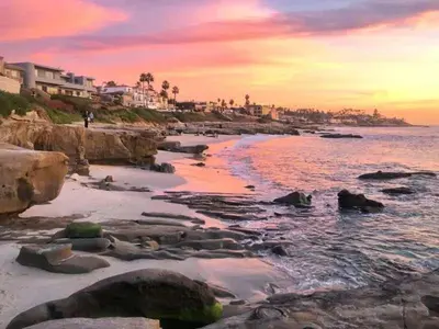 a beach with rocks and the ocean at sunset at Coastal Retreat 1BR Steps to Ocean & Peek Views in San Diego