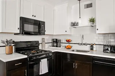 a kitchen with black appliances and white cabinets at Coastal Retreat 1BR Steps to Ocean & Peek Views in San Diego