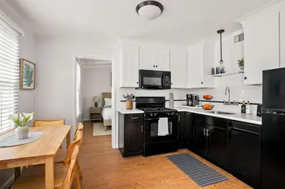 a kitchen with black and white appliances and a table at Beautiful Windansea Beach Compound Steps to Sand in San Diego