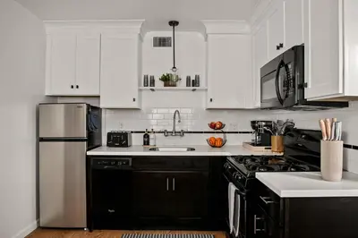 a kitchen with white cabinets and black appliances at Beautiful Windansea Beach Compound Steps to Sand in San Diego