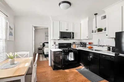 a kitchen with white cabinets and black appliances at Beautiful Windansea Beach Compound Steps to Sand in San Diego