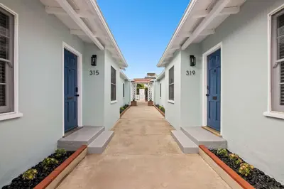 a hallway of white houses with blue doors at Beautiful Windansea Beach Compound Steps to Sand in San Diego