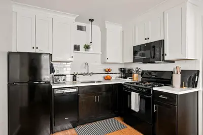 a kitchen with black appliances and white cabinets at Ocean Escape 1BR Walk to Windansea Beach in San Diego