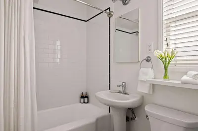 a white bathroom with a sink and a toilet and a tub at Ocean Escape 1BR Walk to Windansea Beach in San Diego