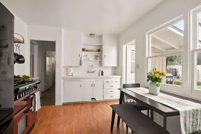 a kitchen with white cabinets and a table with flowers on it at Cozy Coastal Stay Hot Tub & Putting Green in San Diego